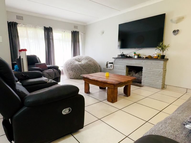 A living room featuring tiled flooring and a central brick fireplace, providing a functional space for relaxation.