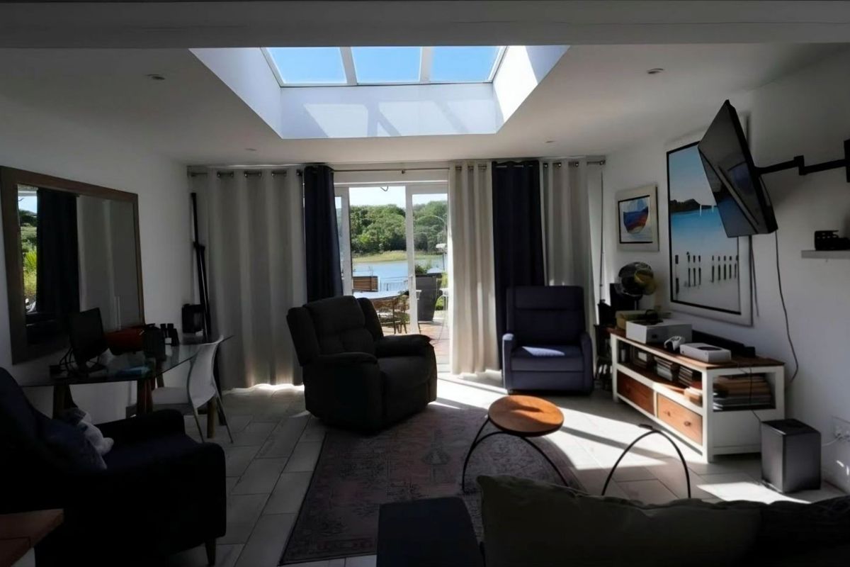 Bright living room featuring a large skylight, tiled flooring, and sliding glass doors that provide natural light and access to the outdoor area.