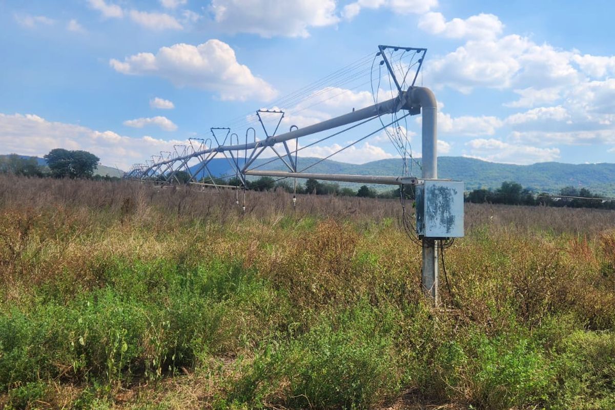 A large-scale center pivot irrigation system installed on agricultural land, featuring a metal support structure and an electrical control unit.
