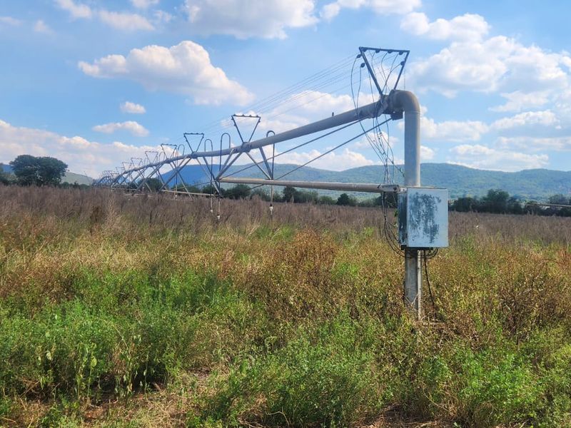 A large-scale center pivot irrigation system installed on agricultural land, featuring a metal support structure and an electrical control unit.