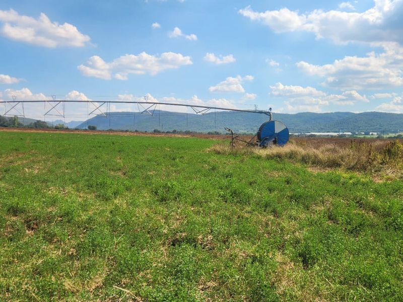 Expansive agricultural farmland featuring a functional center pivot irrigation system set against a scenic mountain backdrop.