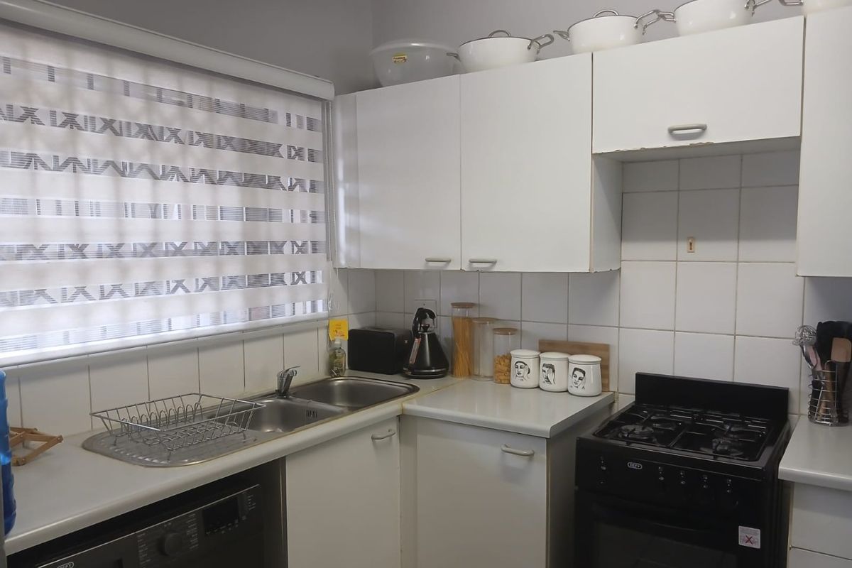 Compact kitchen featuring white cabinetry, laminate countertops, tiled backsplash, and a freestanding stove, providing a functional workspace.