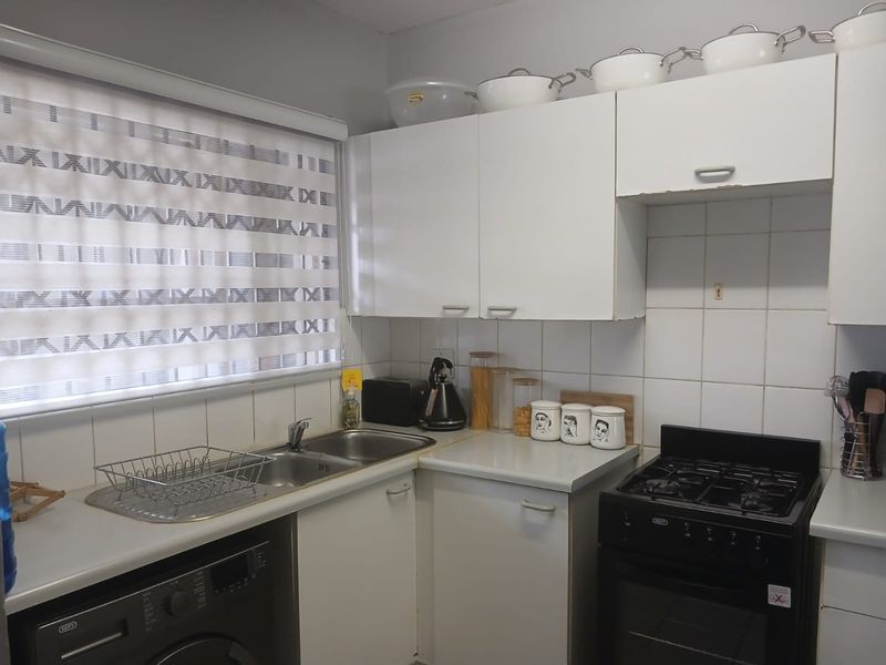 Compact kitchen featuring white cabinetry, laminate countertops, tiled backsplash, and a freestanding stove, providing a functional workspace.