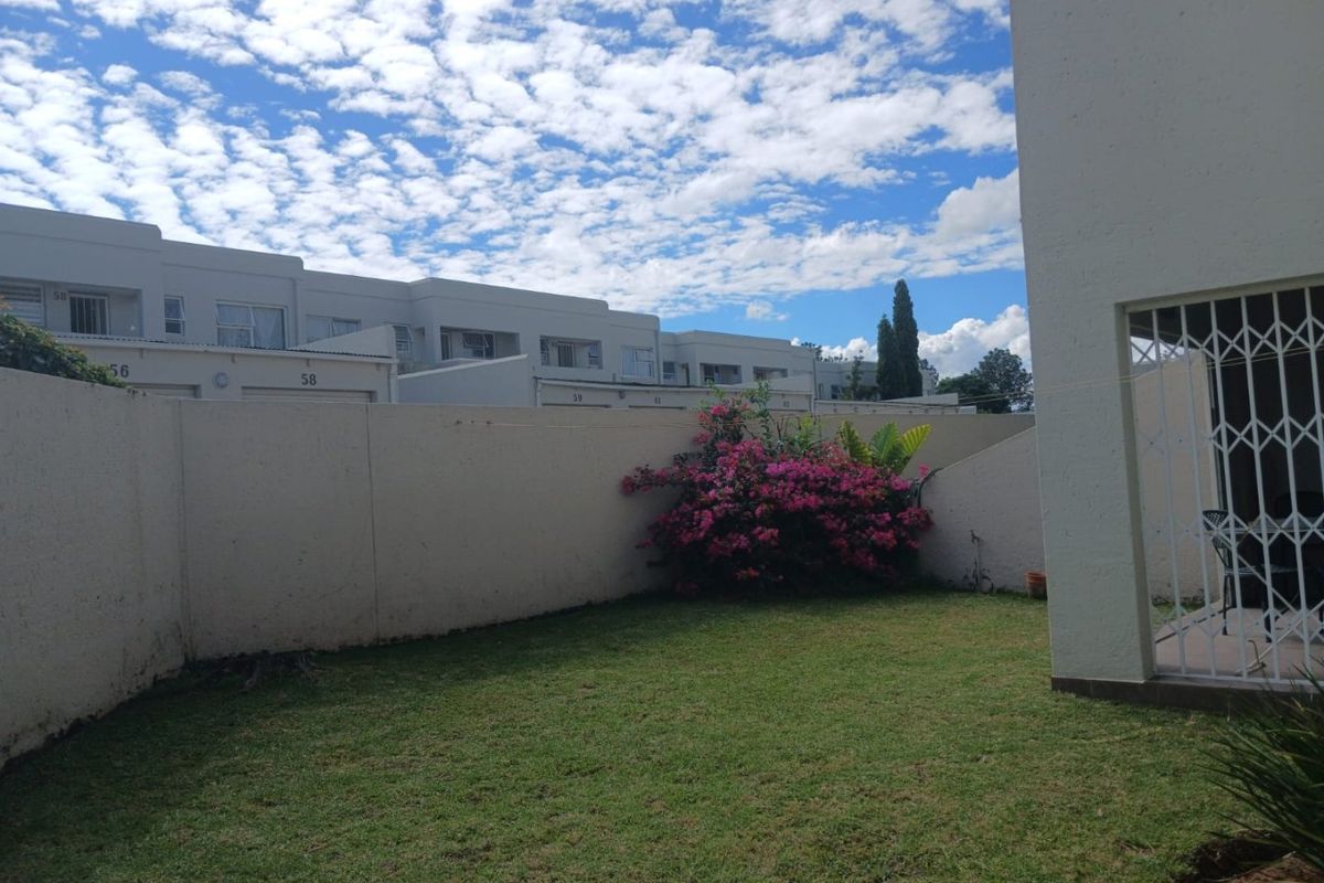 A private rear garden area featuring a lawn, boundary wall, and access to the apartment via a security gate.