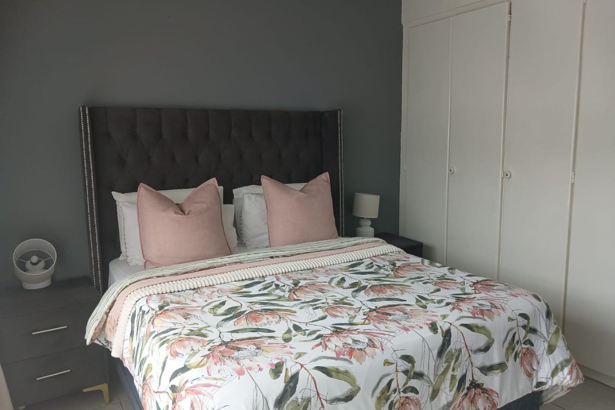 A well-maintained bedroom featuring neutral grey walls and practical built-in cupboards for storage.