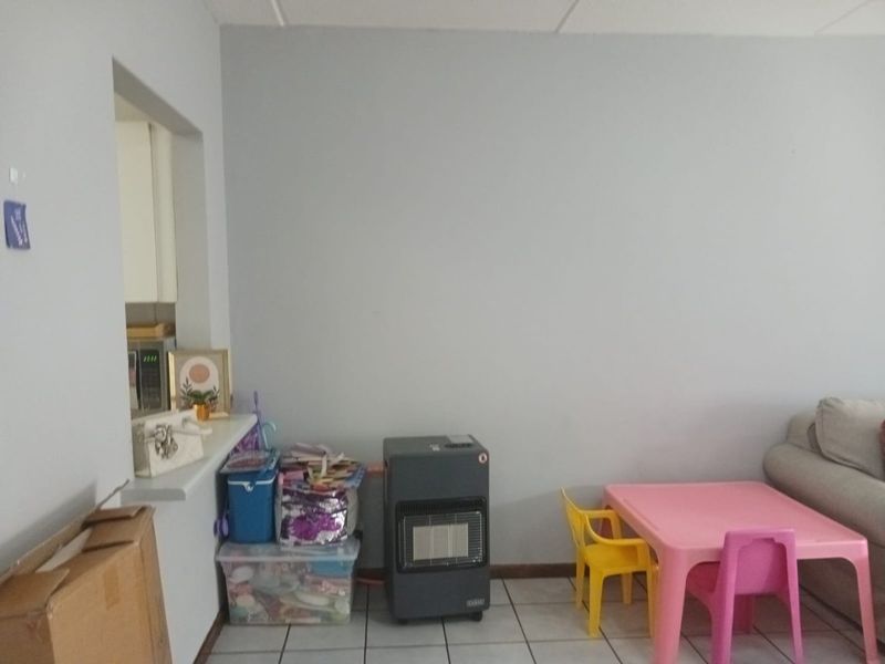 A living area featuring tiled flooring and a convenient pass-through window connecting to the kitchen space.