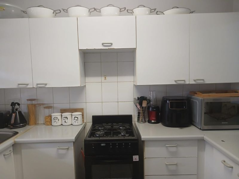 A functional kitchen featuring white cabinetry, a gas stove with oven, tiled backsplash, and laminate countertops.
