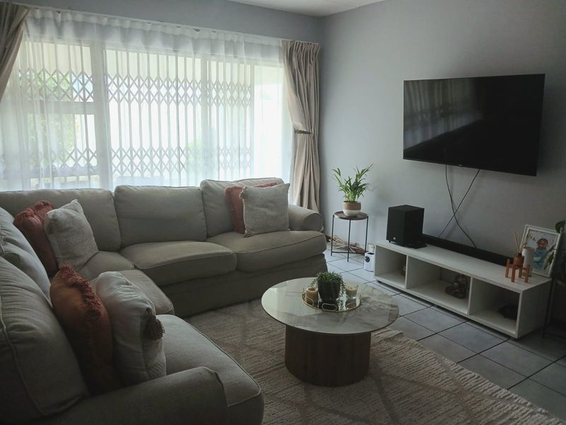A comfortable living room featuring tiled flooring and large windows with security gates, providing a bright and functional space for relaxation.