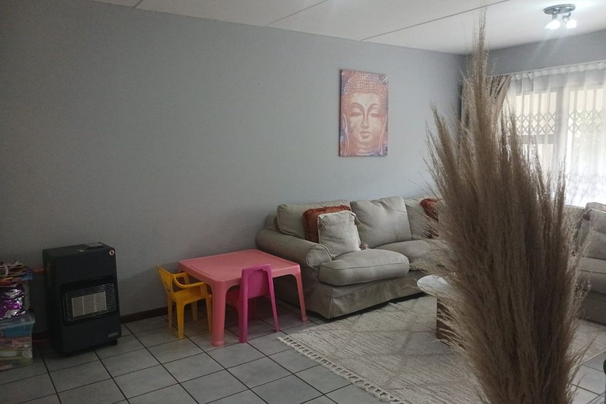 A living room area featuring neutral wall tones and tiled flooring, with a security gate installed at the window.