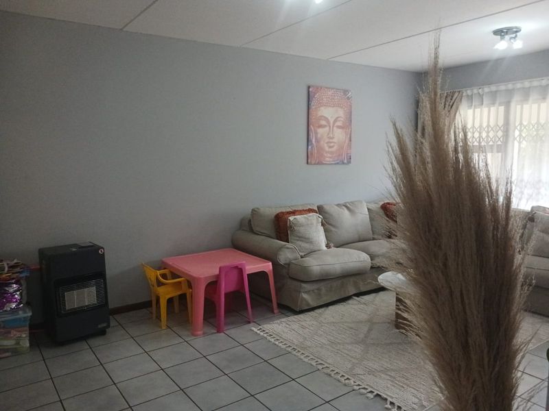 A living room area featuring neutral wall tones and tiled flooring, with a security gate installed at the window.