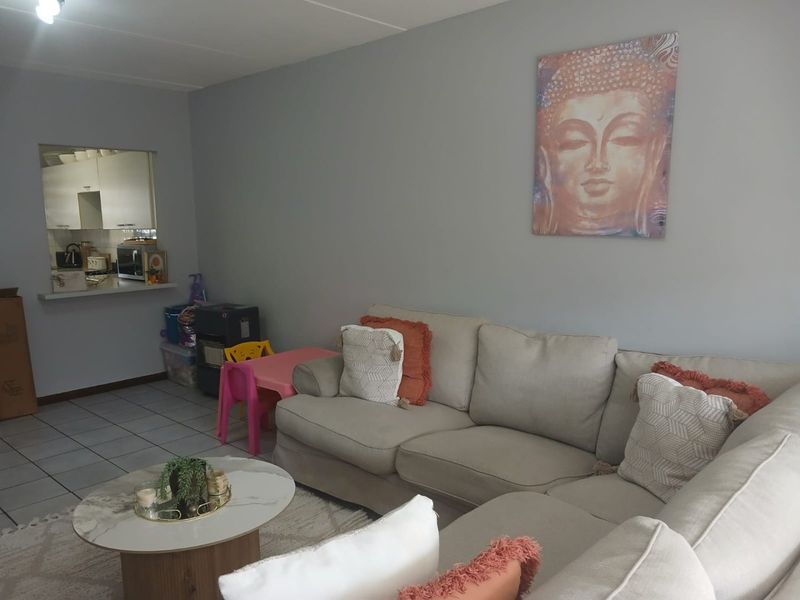Open plan living area featuring tiled flooring and a convenient pass-through window connecting to the kitchen space.