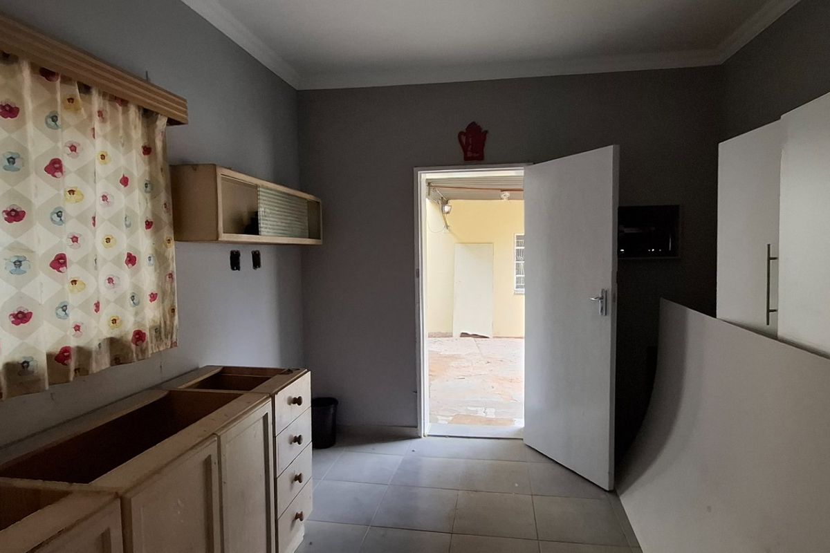 A partially finished kitchen area featuring tiled flooring, built-in cabinetry, and direct access to an outdoor space.