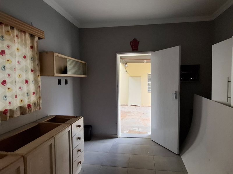 A partially finished kitchen area featuring tiled flooring, built-in cabinetry, and direct access to an outdoor space.