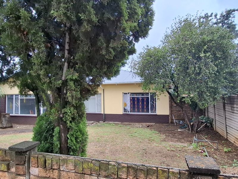 Rear view of the property featuring a garden area, brick boundary wall, and precast concrete fencing.