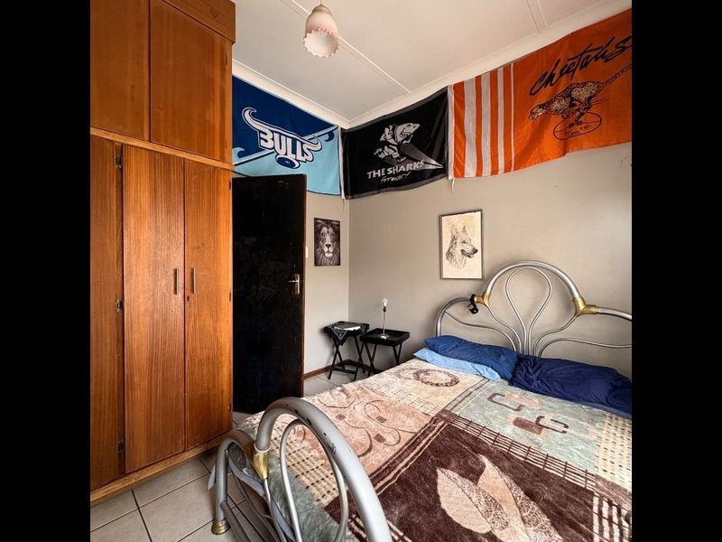 A bedroom featuring tiled flooring and a built-in wooden wardrobe, providing functional storage space.