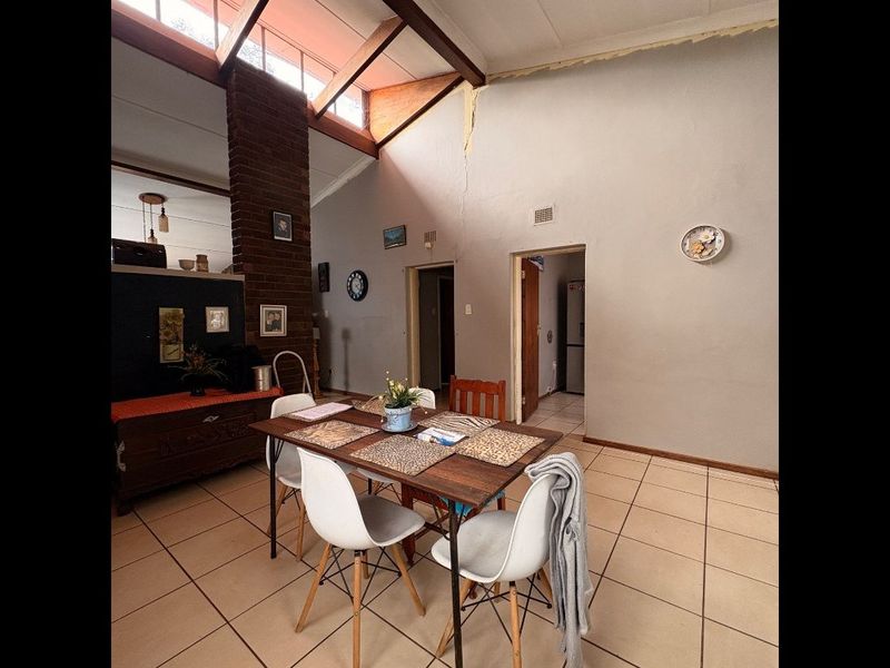Spacious living area featuring a vaulted ceiling, exposed brick chimney breast, and clerestory windows, offering a unique architectural layout with tiled flooring throughout.