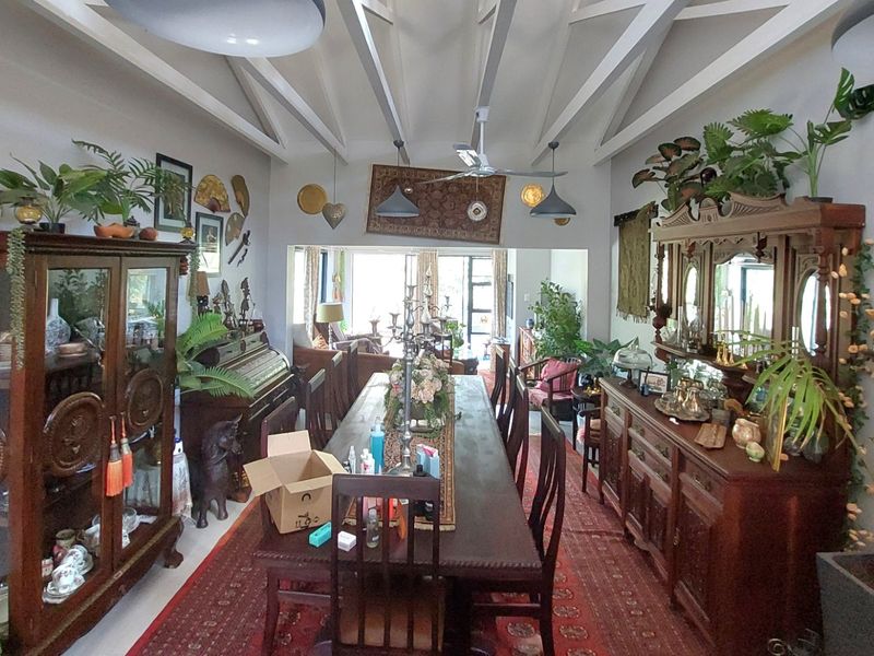 Spacious dining area featuring exposed timber ceiling beams, ceiling fan, and pendant lighting, creating a character-filled space for formal meals.