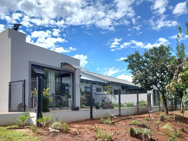 Rear view of the townhouse featuring a paved patio, sliding glass doors, and a well-maintained garden with perimeter fencing.