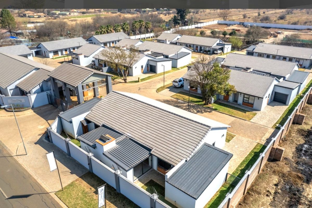 Aerial view of a modern townhouse complex featuring multiple residential units, paved driveways, and a secure gated entrance.