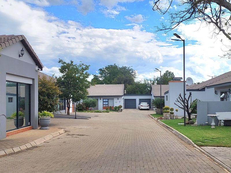 A view of the paved complex driveway featuring multiple townhouse units with tiled roofs and garage access.