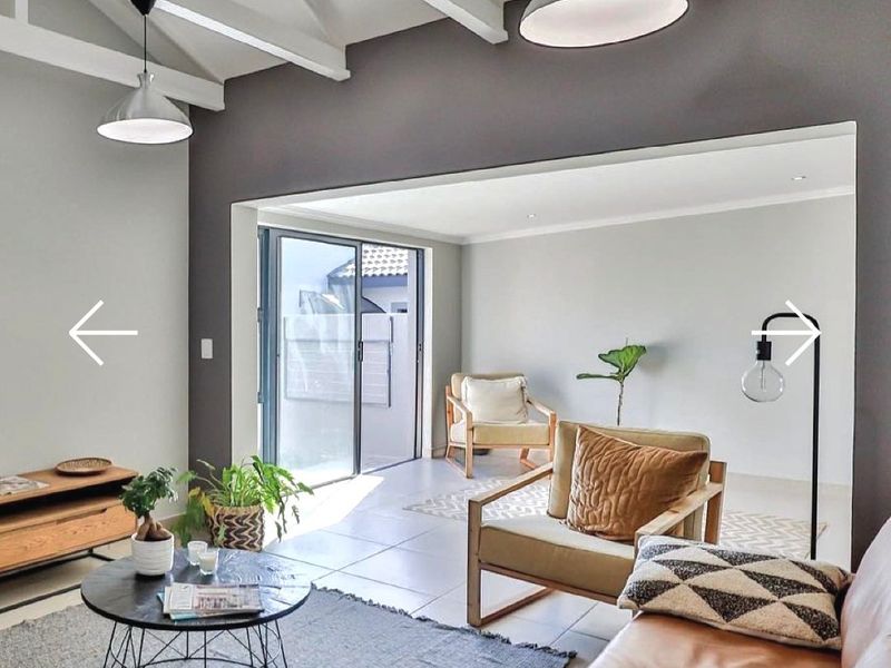 Bright open-plan living area featuring exposed timber rafters, tiled flooring, and large sliding glass doors leading to an outdoor space.
