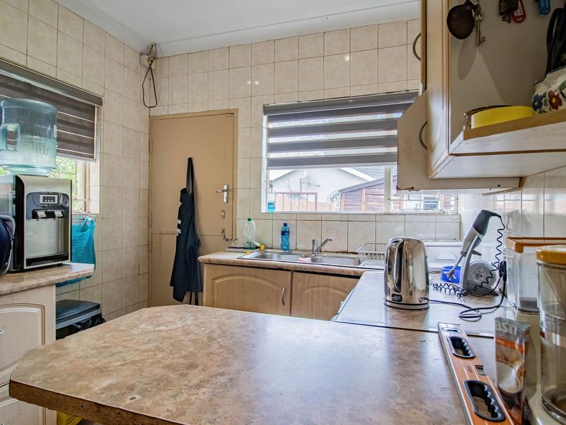 A functional kitchen featuring laminate countertops, tiled backsplash, and built-in cabinetry, offering a practical layout with potential for modern cosmetic updates.