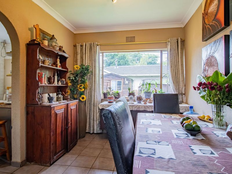 A dining room featuring tiled flooring, a coved ceiling, and an arched entryway leading to the kitchen area.