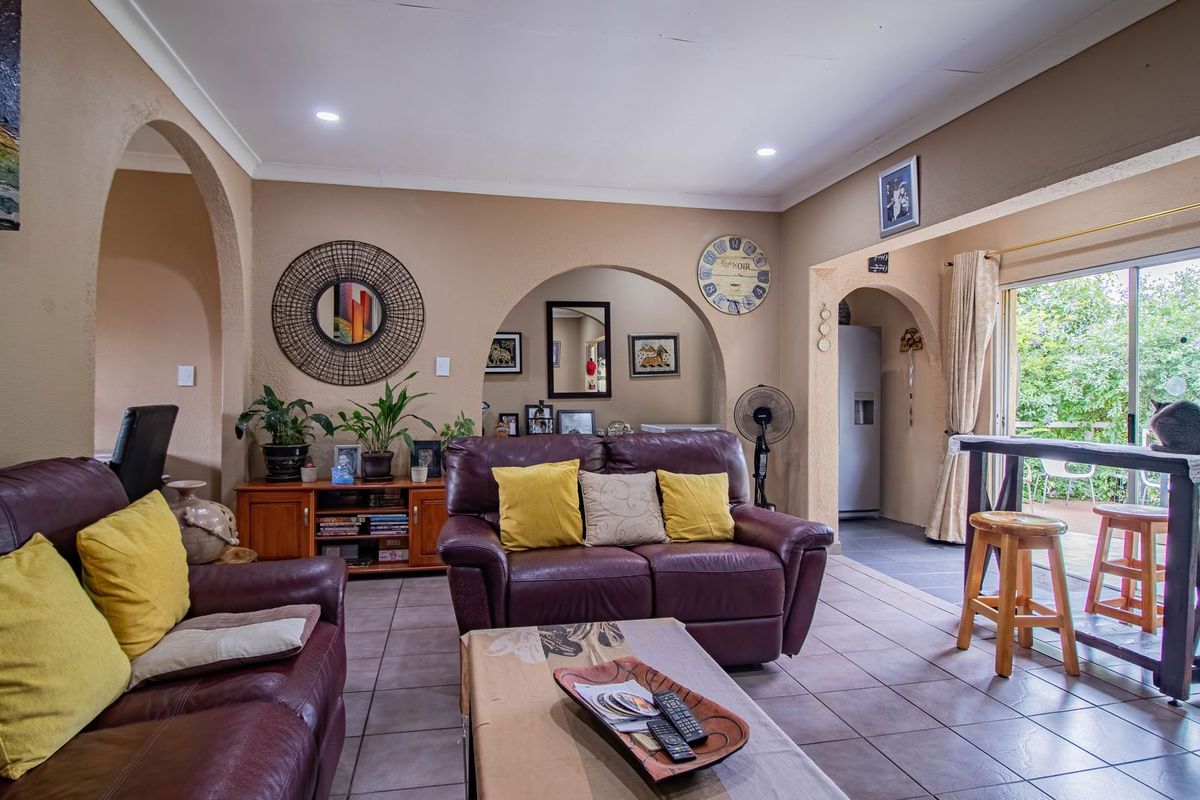 A comfortable living room featuring tiled flooring, recessed lighting, and arched architectural details, with direct access to an outdoor patio area through sliding glass doors.