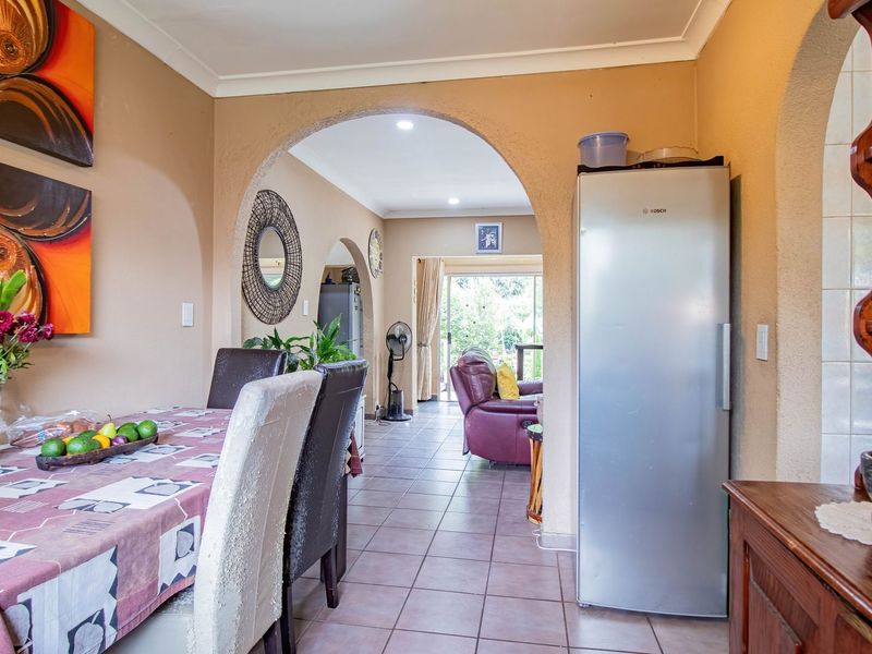 Open plan dining area featuring tiled flooring and distinctive arched doorways leading through to the living space and garden access.