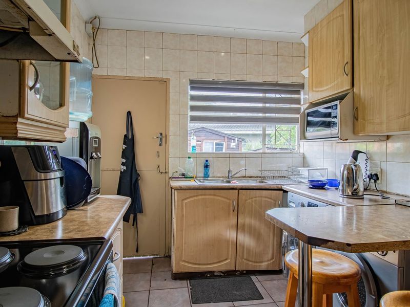 A functional kitchen featuring laminate cabinetry, tiled backsplash, and built-in appliances, offering a practical layout with potential for modern cosmetic updates.