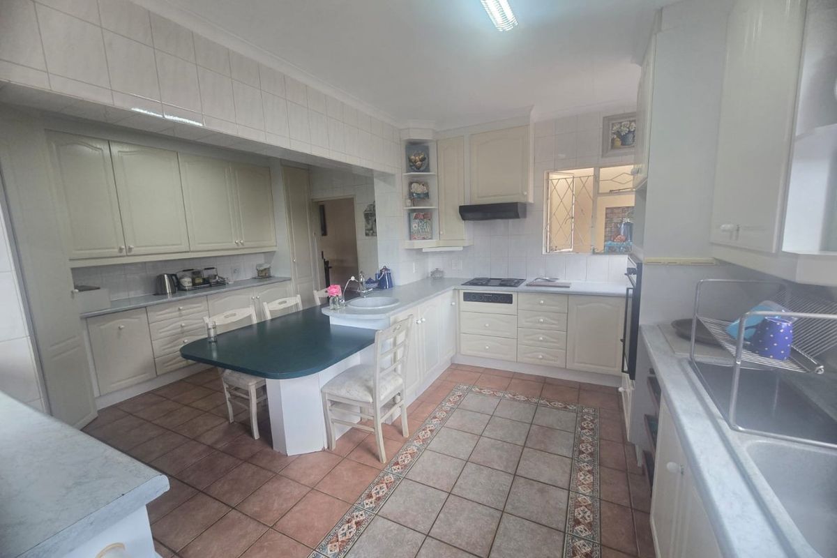 A functional kitchen featuring built-in cabinetry, integrated appliances, tiled flooring, and a breakfast nook area, offering potential for modern updates.