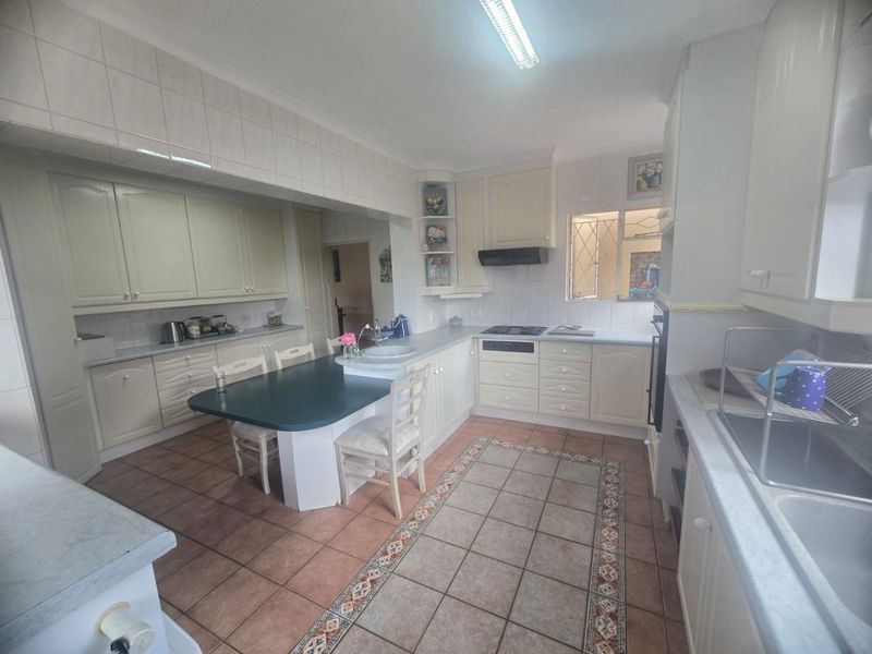 A functional kitchen featuring built-in cabinetry, integrated appliances, tiled flooring, and a breakfast nook area, offering potential for modern updates.