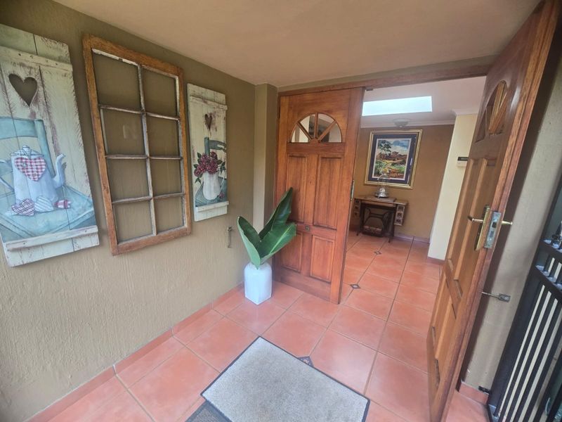 Entrance foyer featuring terracotta floor tiles, a timber front door, and a skylight providing natural light to the interior space.