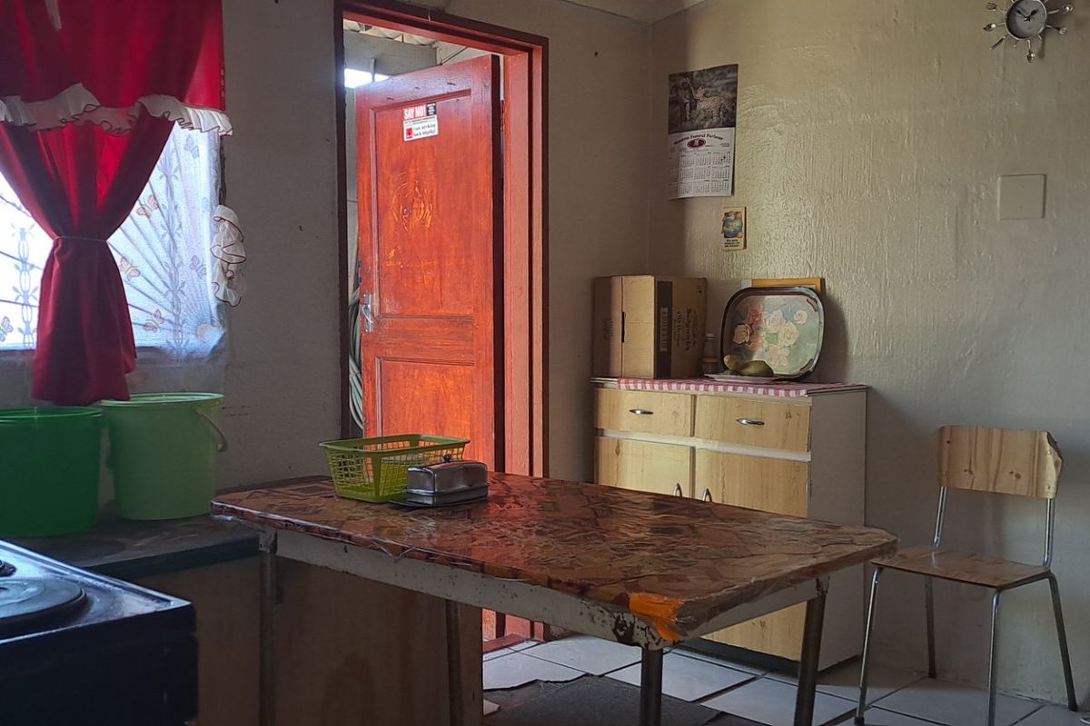 A functional kitchen space featuring basic cabinetry, an electric stove, and tiled flooring, offering potential for modernization and cosmetic updates.