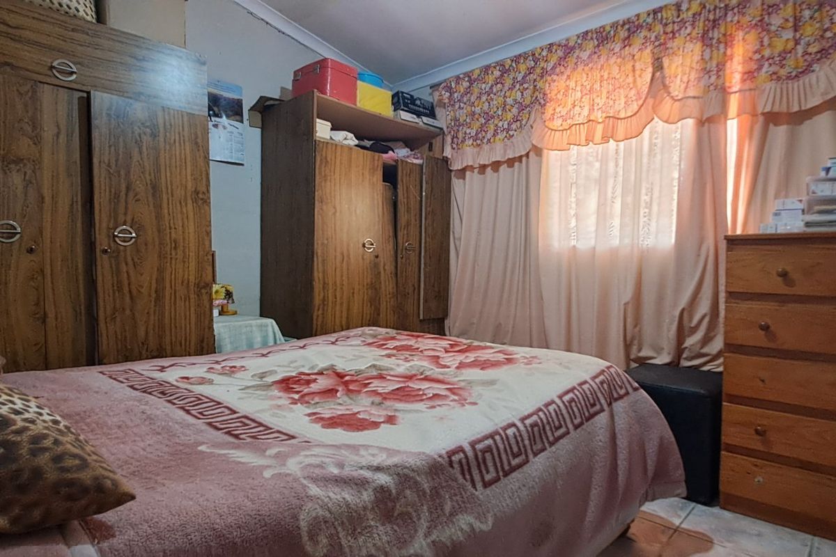 A bedroom featuring tiled flooring and a window with curtain treatments.