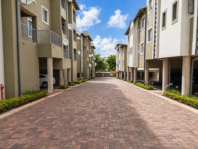 A view of the apartment complex driveway featuring paved surfaces, covered parking areas, and residential balconies.