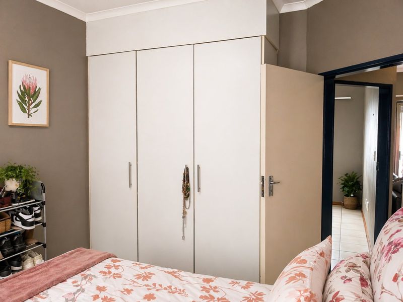 A bedroom featuring a white built-in wardrobe with modern handles and neutral wall tones.