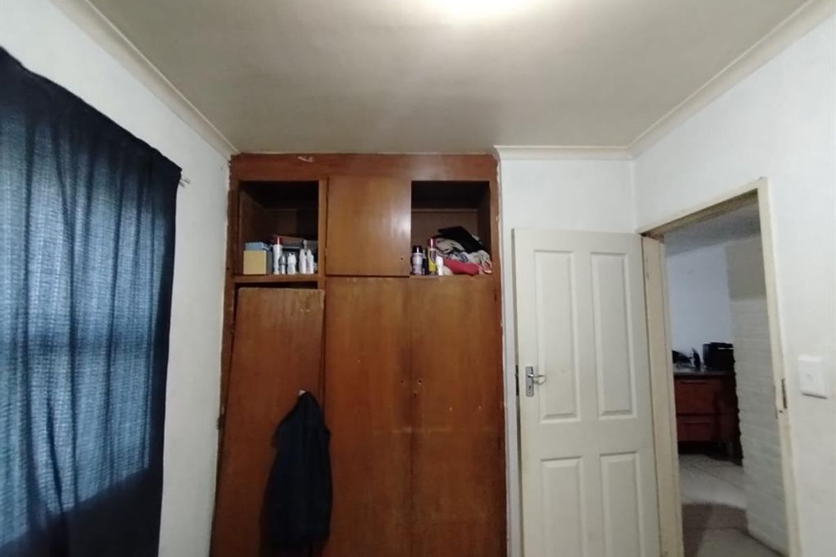 A bedroom featuring built-in wooden cupboards and standard internal door access, requiring cosmetic updates to improve the overall aesthetic.