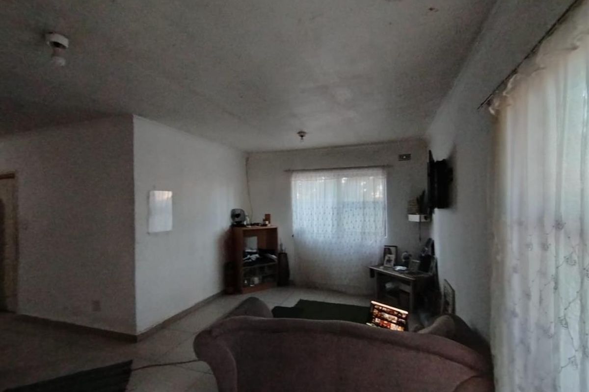 A living room area featuring tiled flooring and basic ceiling fixtures, requiring cosmetic updates to improve the overall aesthetic and condition of the space.