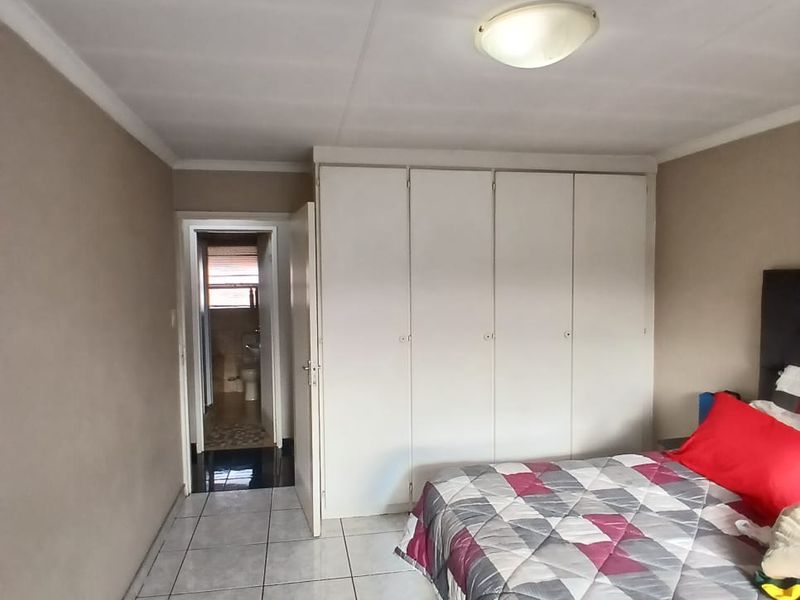 Bedroom featuring built-in cupboards, tiled flooring, and direct access to an en-suite bathroom.