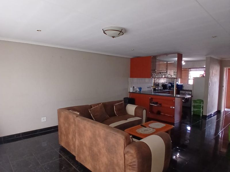 Open plan living area featuring dark tiled flooring and a kitchen with built-in cabinetry and a breakfast bar.