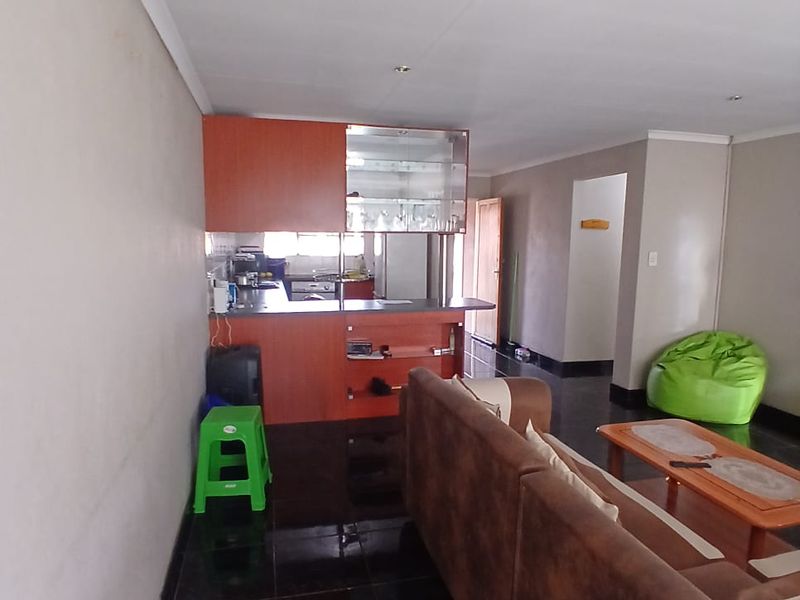 Open plan living area featuring a kitchen with breakfast bar and dark tiled flooring throughout the combined space.