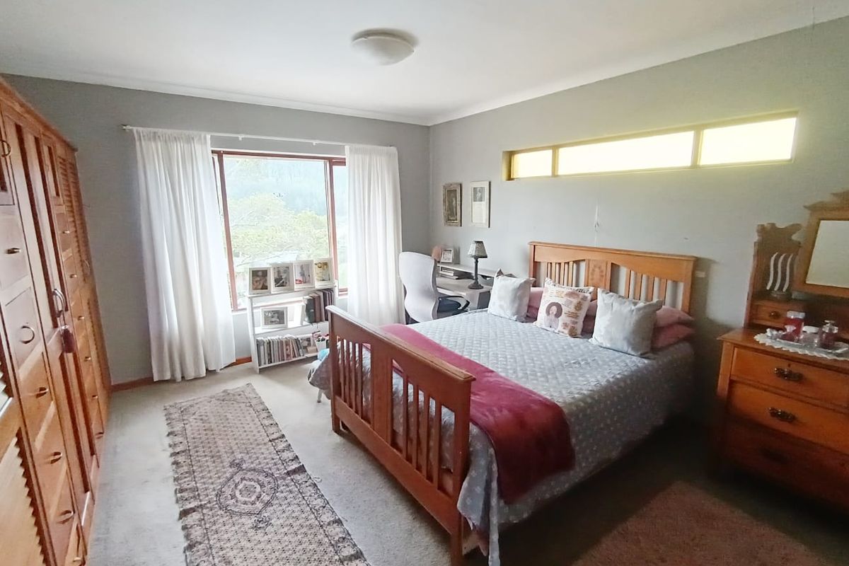Spacious bedroom featuring built-in cupboards, a large picture window for natural light, and a high-level clerestory window.