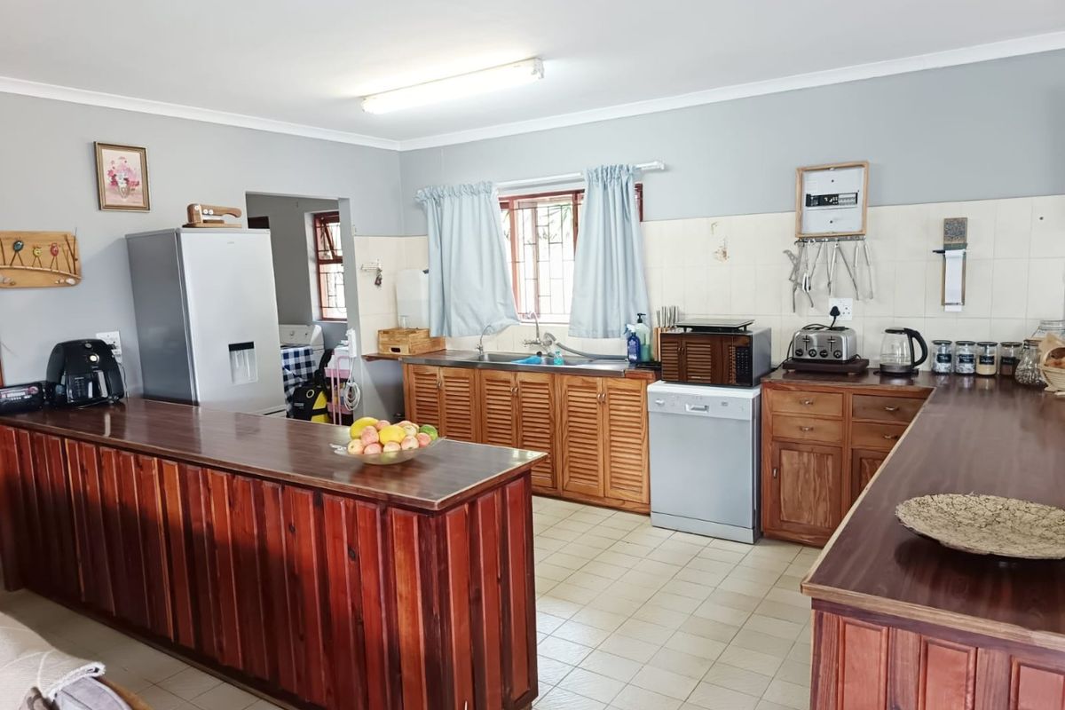 A functional kitchen featuring wooden cabinetry, a breakfast bar, tiled flooring, and a tiled backsplash, offering a traditional layout with ample counter space.