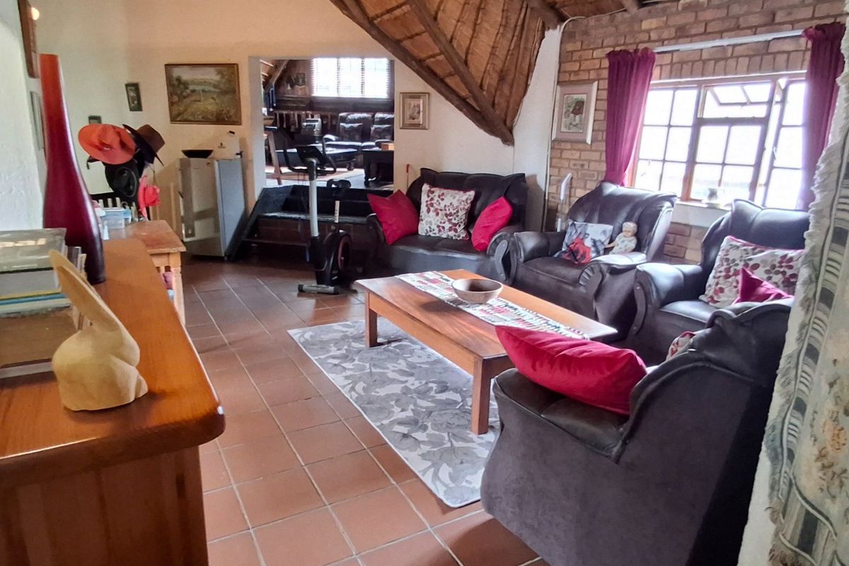 A rustic living room featuring exposed brick walls, a traditional thatched roof ceiling, and terracotta floor tiles, offering a warm and characterful living space.