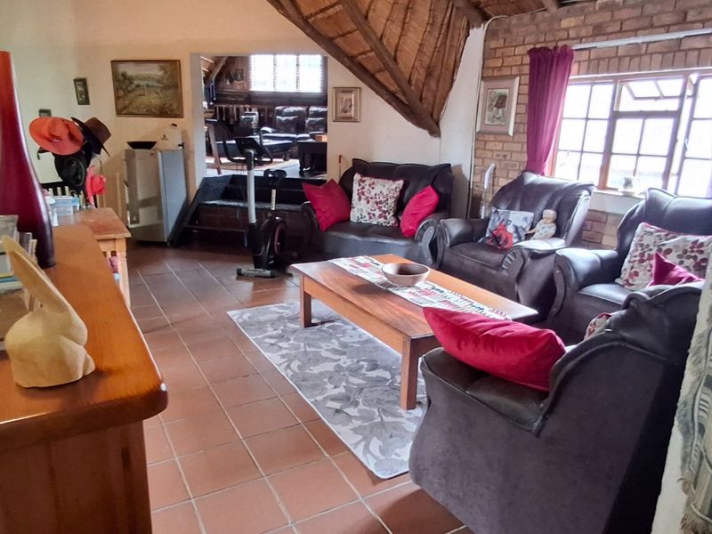 A rustic living room featuring exposed brick walls, a traditional thatched roof ceiling, and terracotta floor tiles, offering a warm and characterful living space.