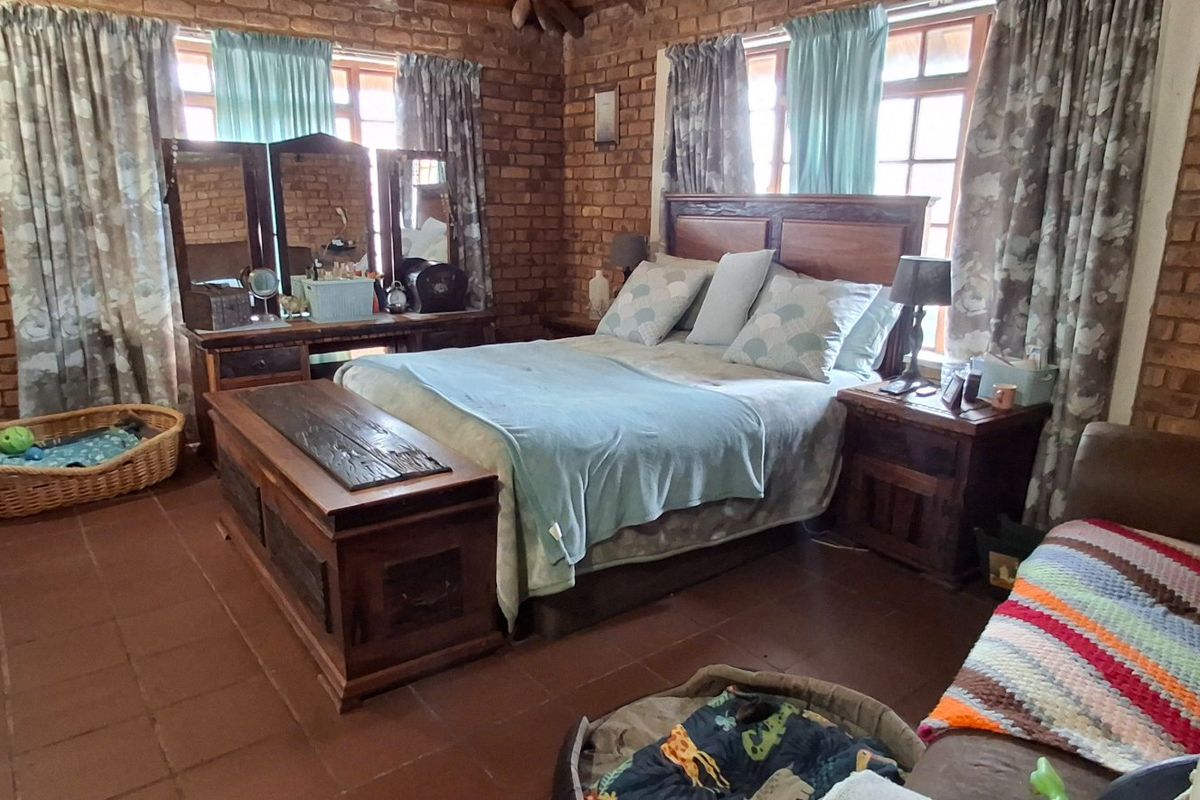 A rustic bedroom featuring exposed brick walls, tiled flooring, and timber-framed windows, offering a warm and traditional aesthetic.
