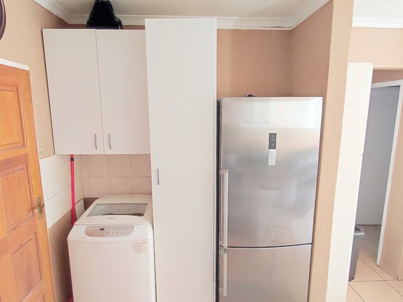 A functional laundry area featuring built-in white cabinetry and tiled splashback, providing dedicated space for laundry appliances.