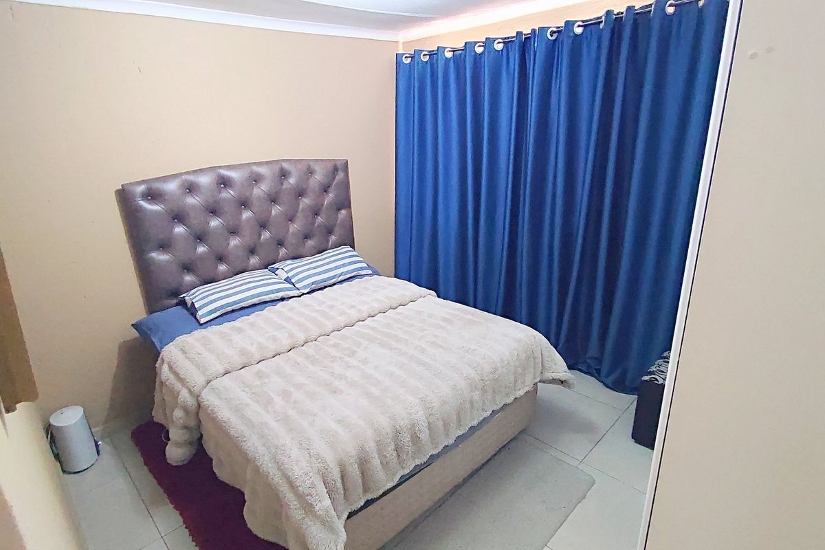 A standard bedroom featuring tiled flooring and a built-in cupboard, providing a functional and neutral living space.
