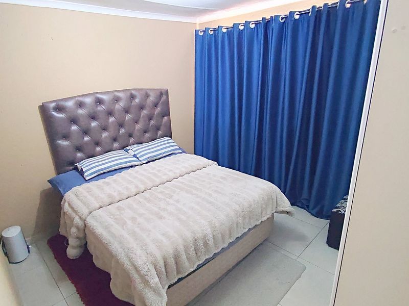 A standard bedroom featuring tiled flooring and a built-in cupboard, providing a functional and neutral living space.